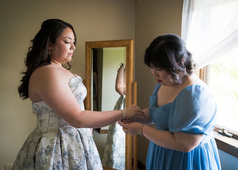 A sequence of getting ready moments showing someone helping another person put on a blue dress.
