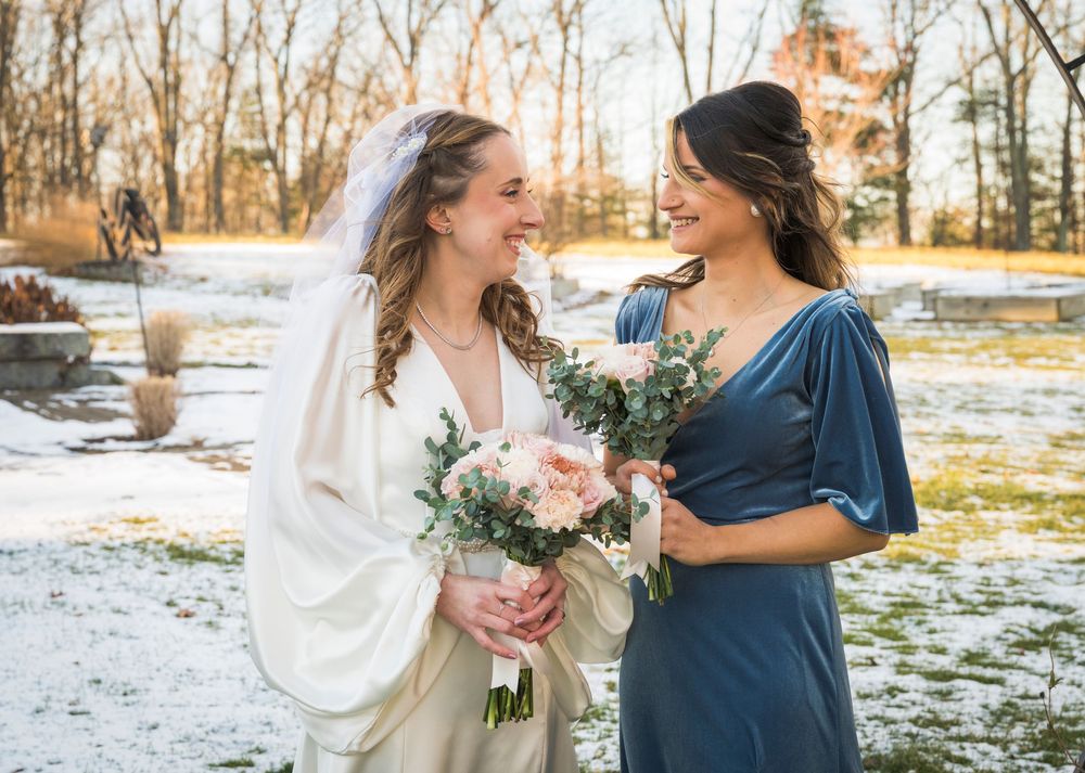 Wedding party members in winter sharing joyful moments together in a snowy outdoor setting.
