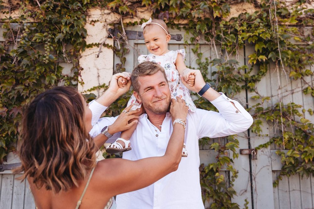 Candid parents laughing with daughter outdoors captured by Santa Barbara family photographer