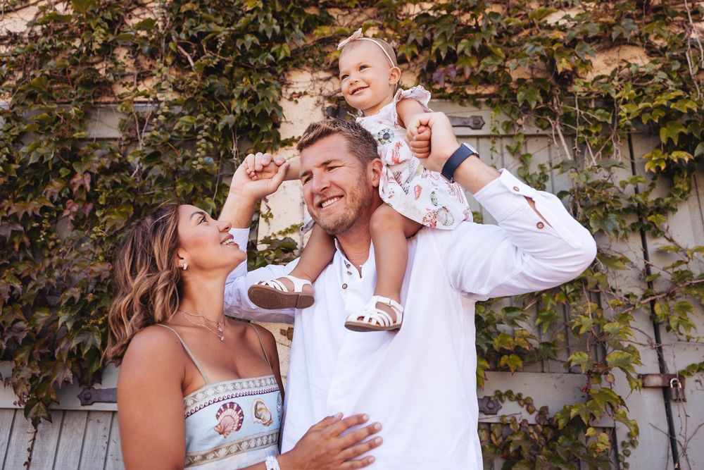 A joyful family moment captured against a wall covered in autumn foliage.