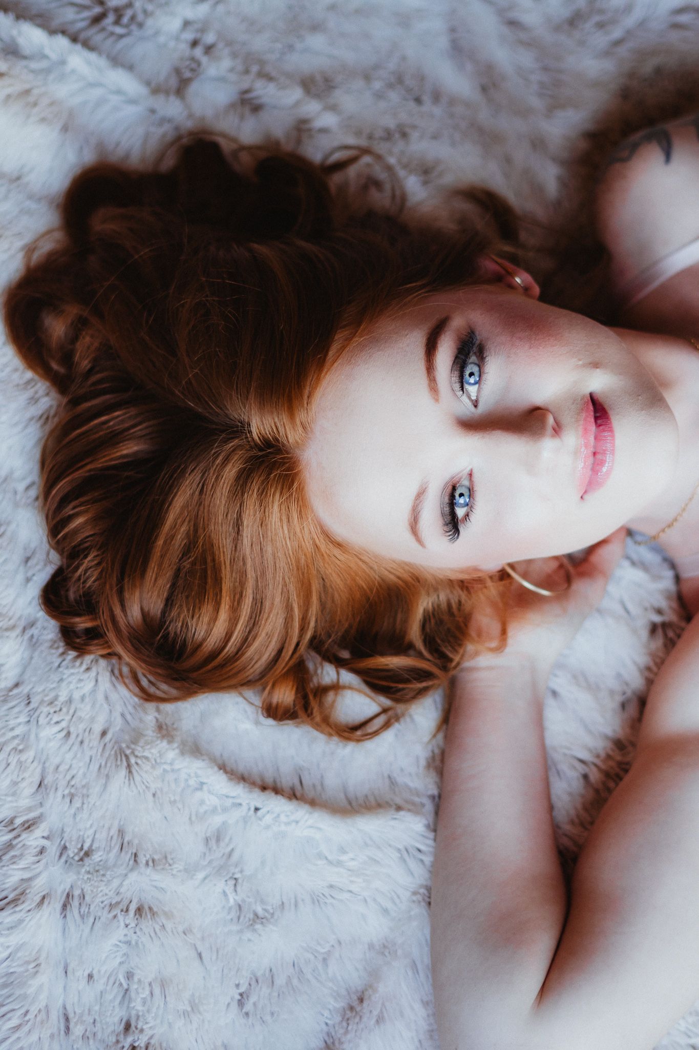 Artistic portrait on white fur background showing soft natural lighting.