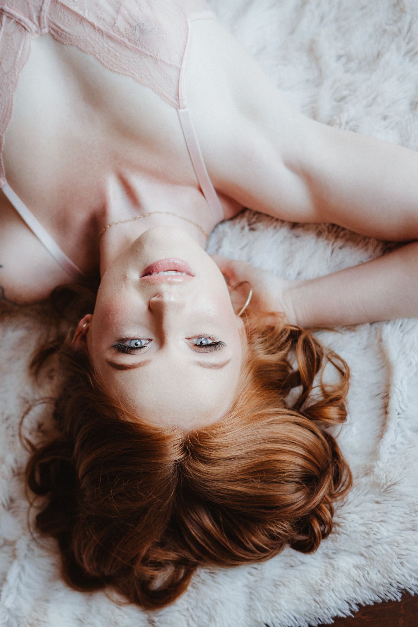 Soft portrait photography on white fur rug with gentle lighting.