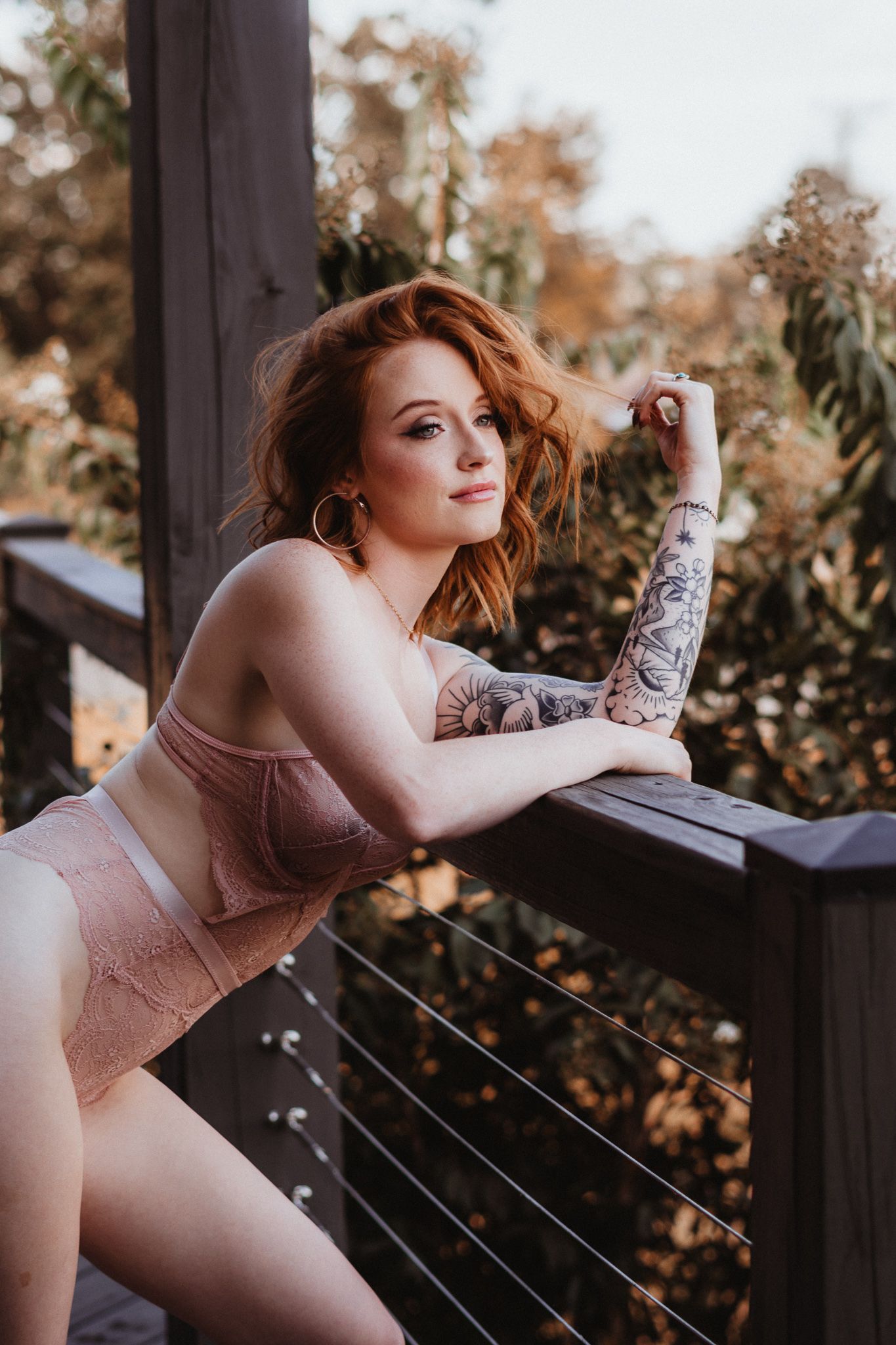 Outdoor boudoir photography session on wooden deck with autumn foliage.