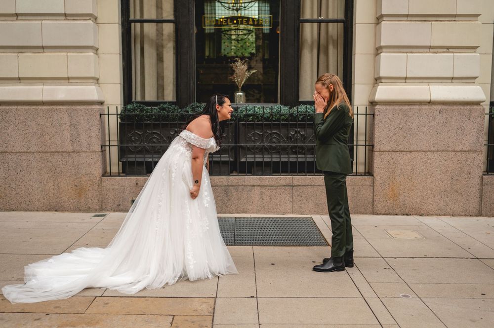 Wedding couple poses on historic stone steps of an elegant building while photographer captures their special moment.