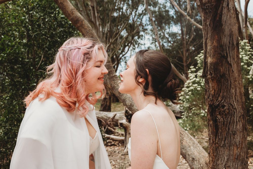 In a forest setting, two people share intimate candid moments during a photo session.