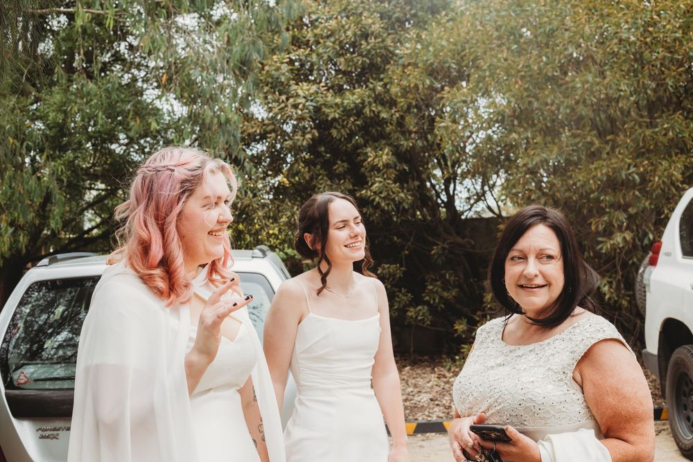 A joyful outdoor celebration with laughter and smiles shared among a group in white attire at a summer event.