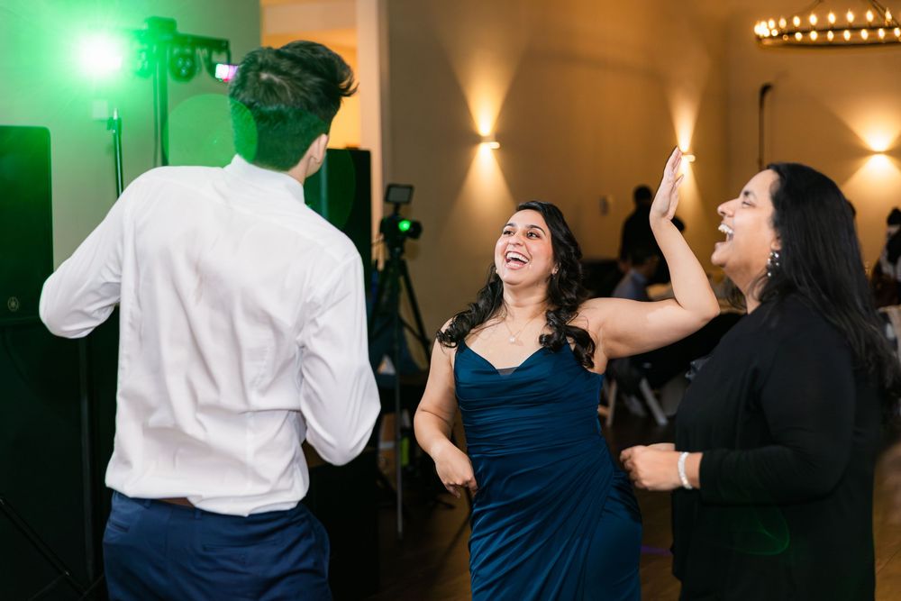 People dance together at an indoor event venue with alternating warm and green lighting effects.