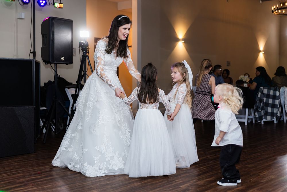 Wedding reception dance floor scene with people in formal attire and white decor.