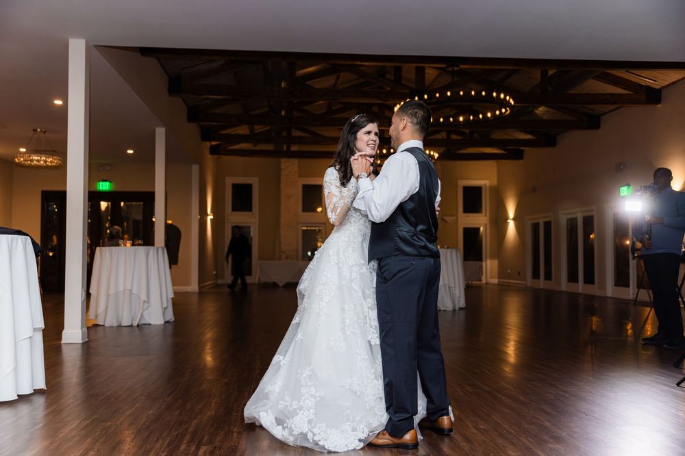 Newlywed couple dancing together in an elegant reception venue with a polished wood floor.
