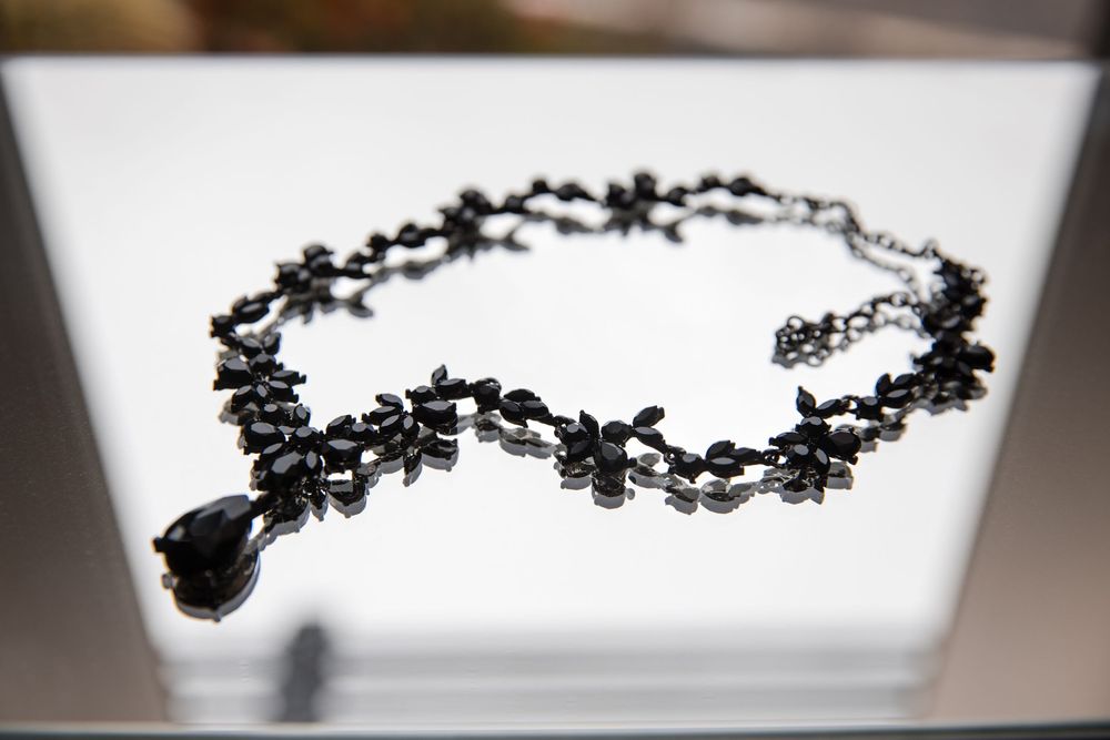 Delicate black floral wedding jewelry necklace displayed on white background.
