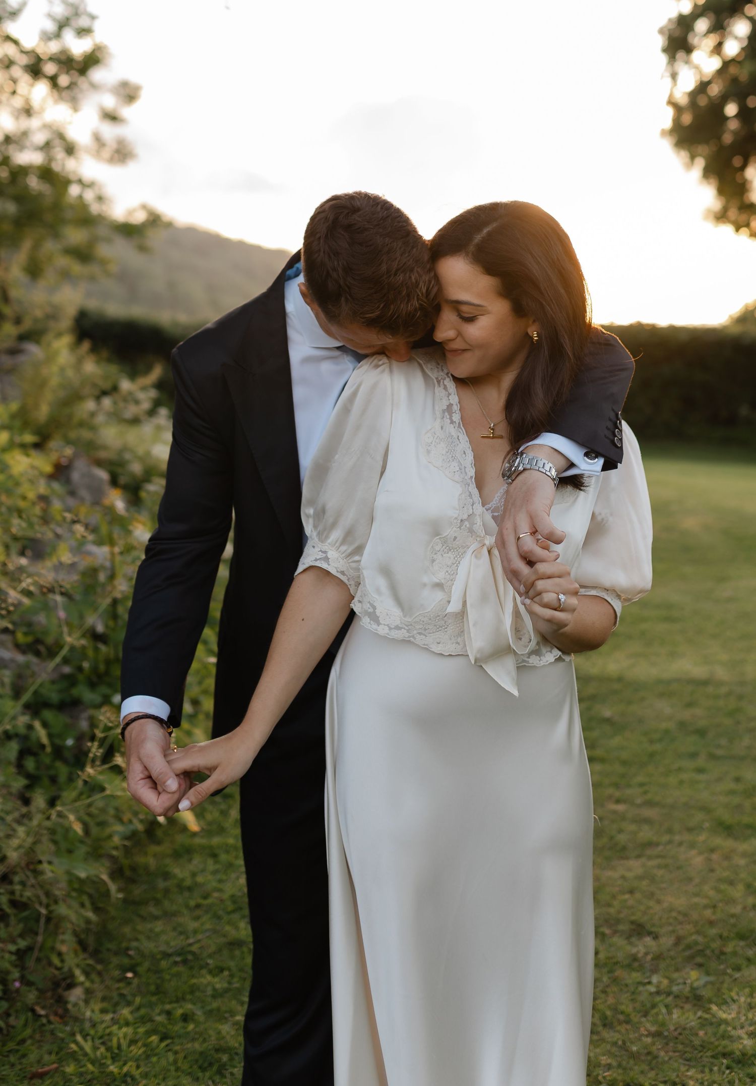 A couple shares an intimate moment on a tree-lined dirt path during a romantic outdoor photo session.