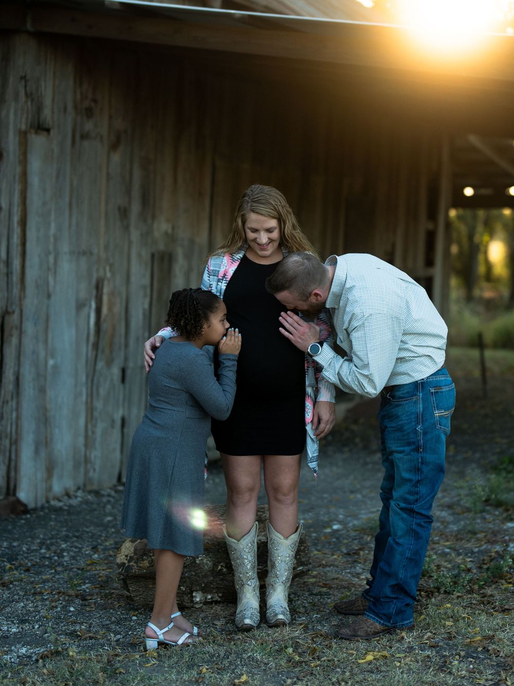 A heartwarming sunset photoshoot by a rustic barn featuring white cowboy boots and casual country attire.