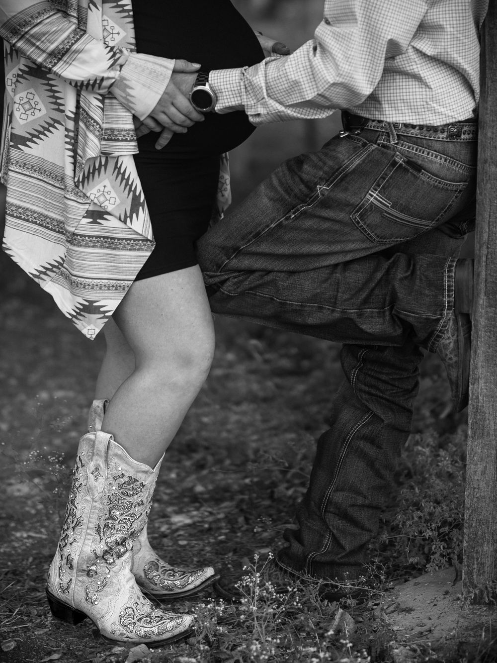 Black and white detail shot of cowboy boots and denim in a romantic pose.