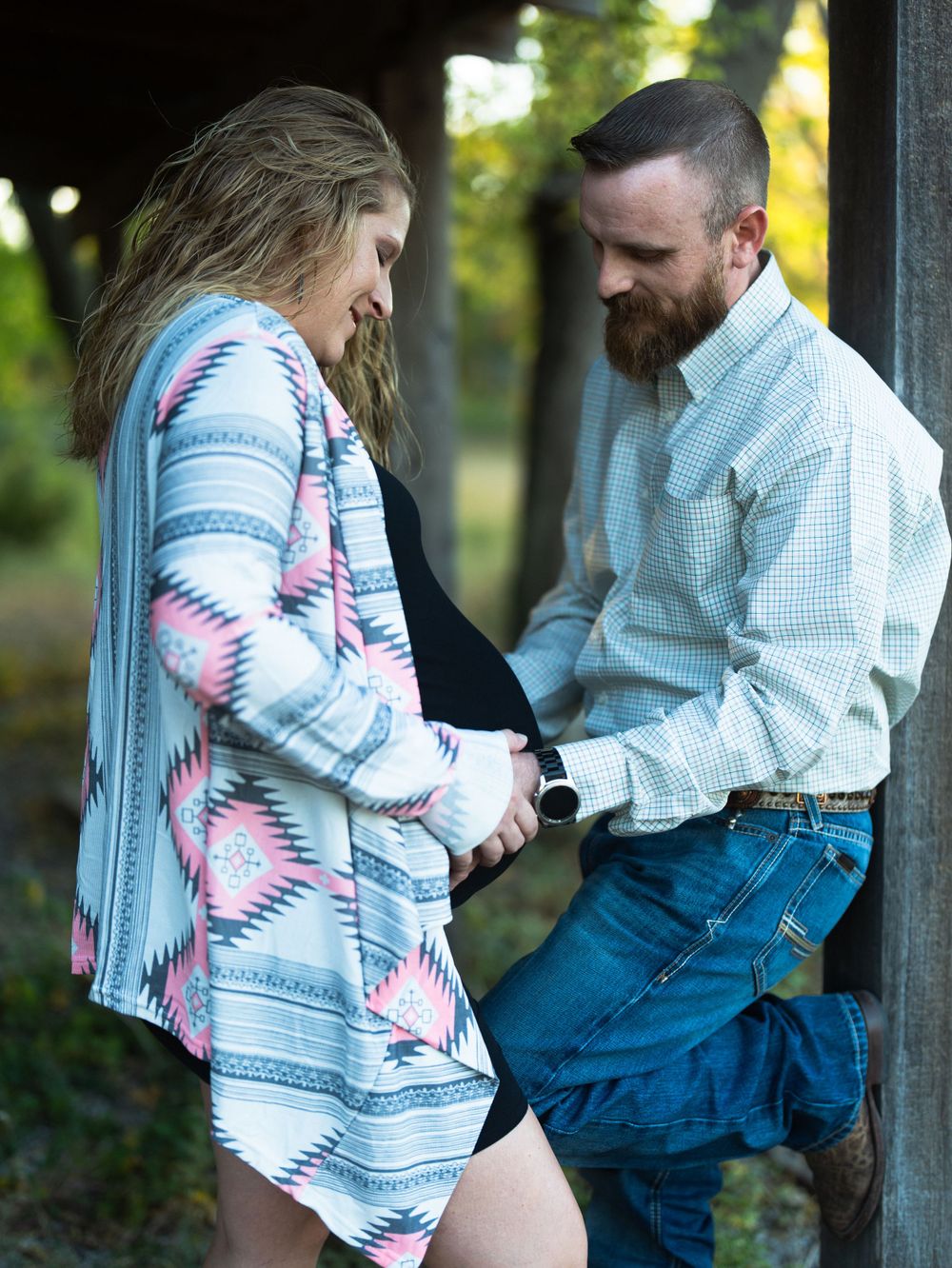 Sweet moment between couple by rustic barn wearing southwestern-inspired clothing.