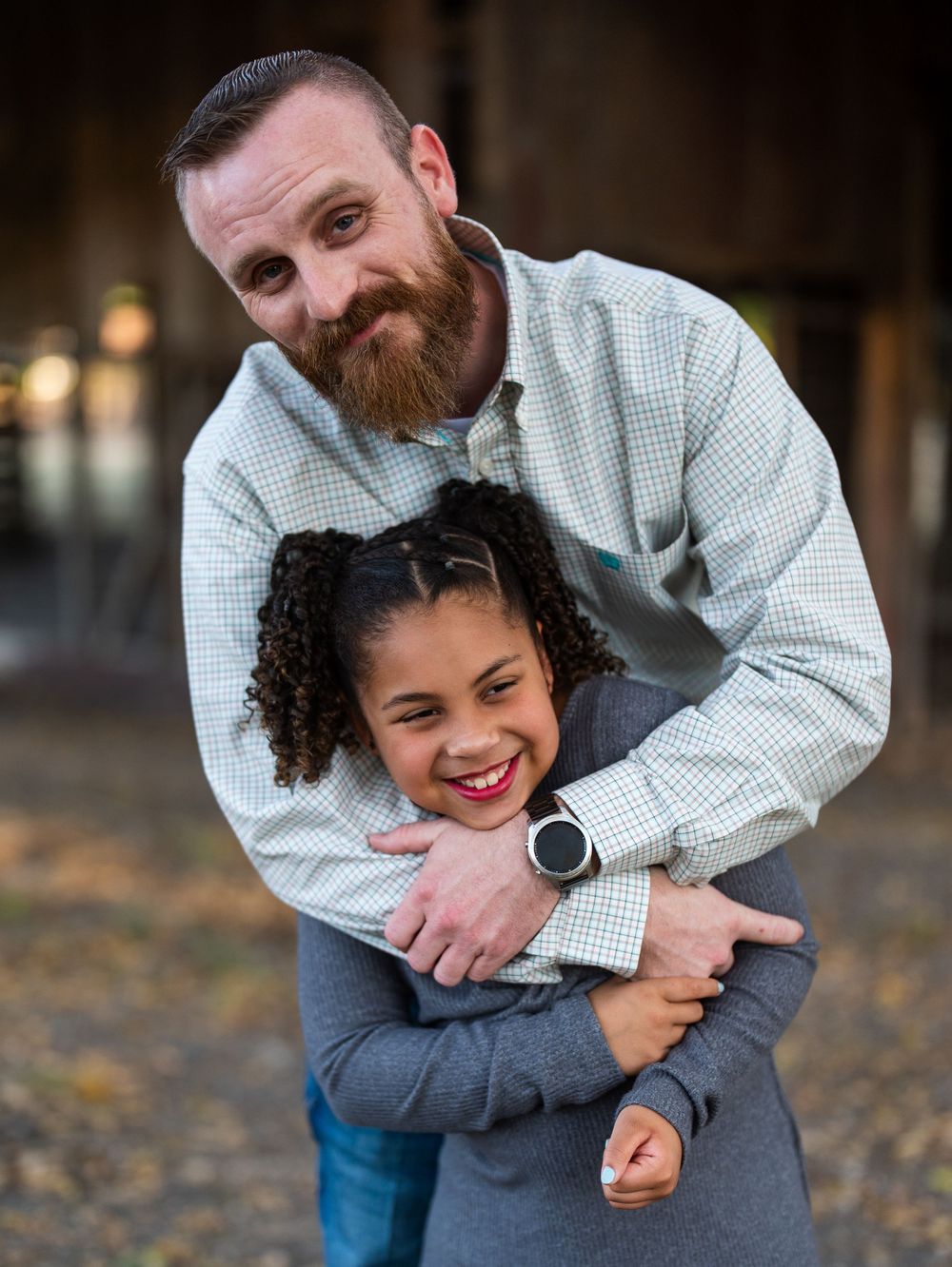 Candid moment of shared laughter during an outdoor portrait session near a rustic barn.