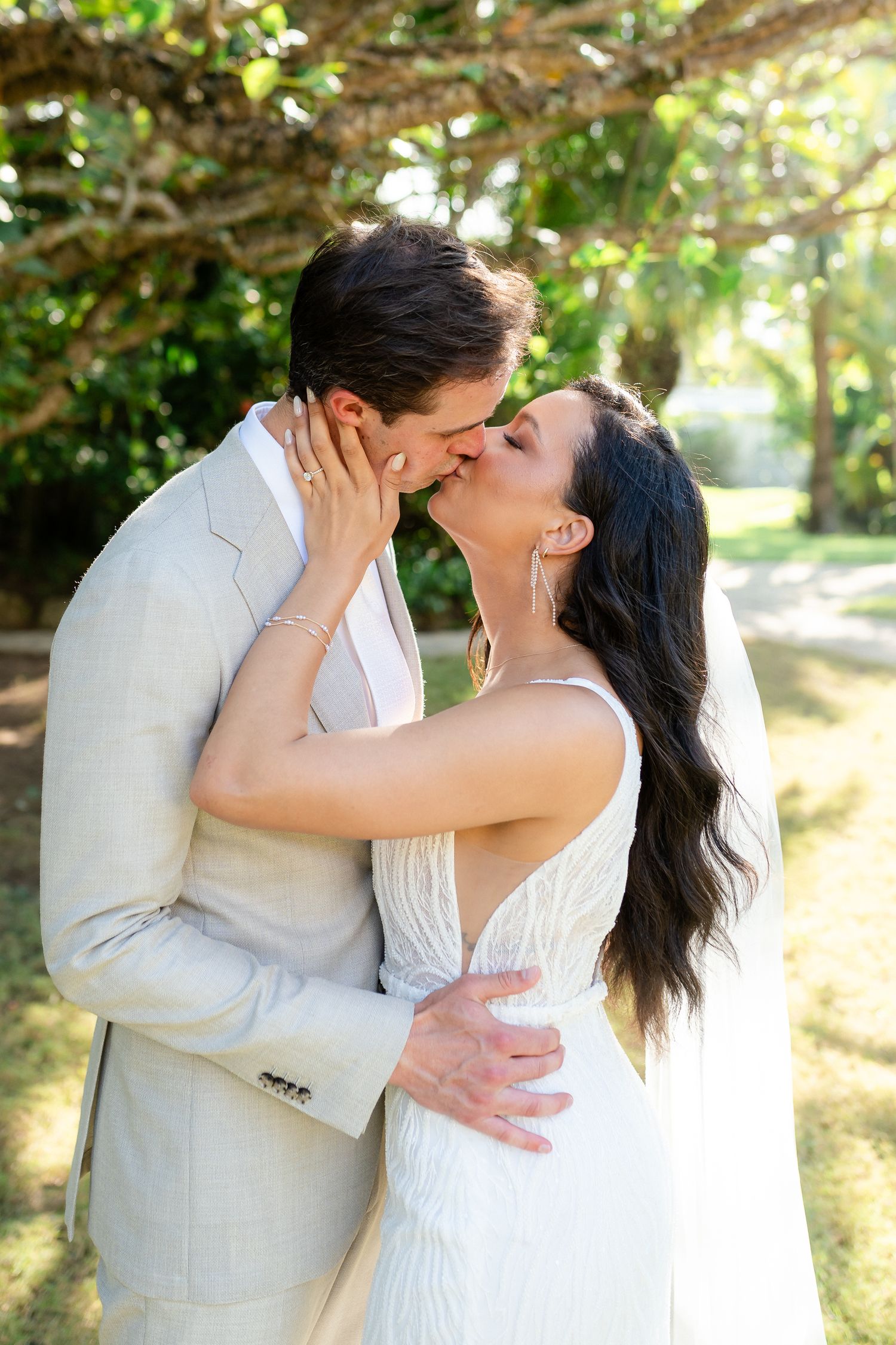 Romantic wedding couple embracing outdoors under natural garden canopy.