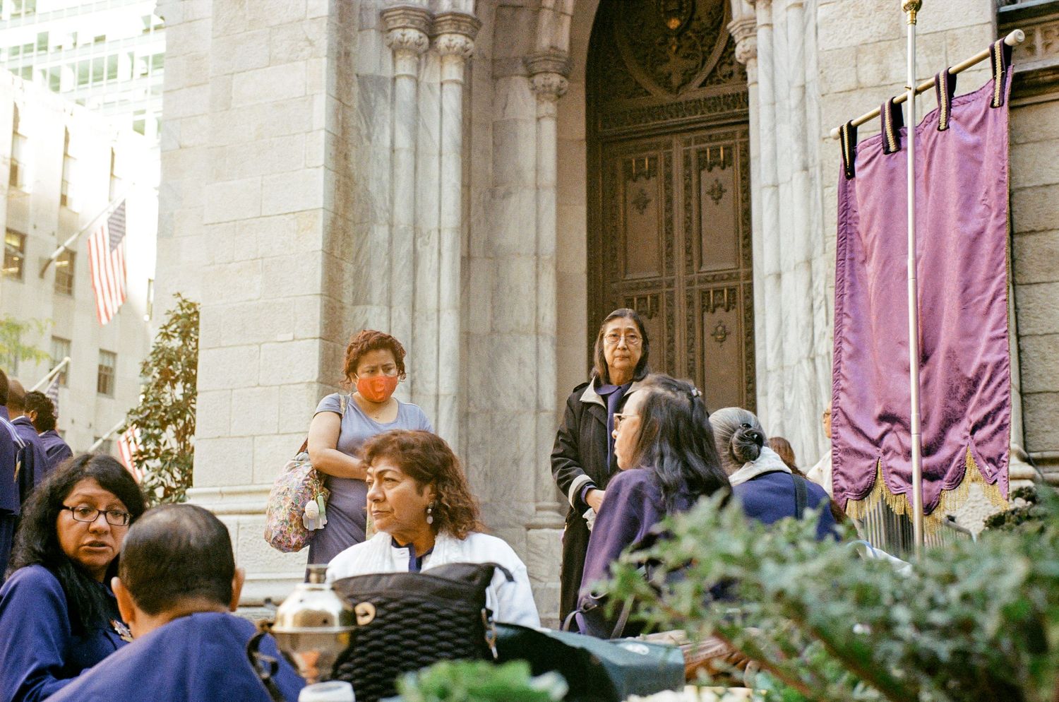 A group gathers on church steps during a sunny afternoon in New York City.