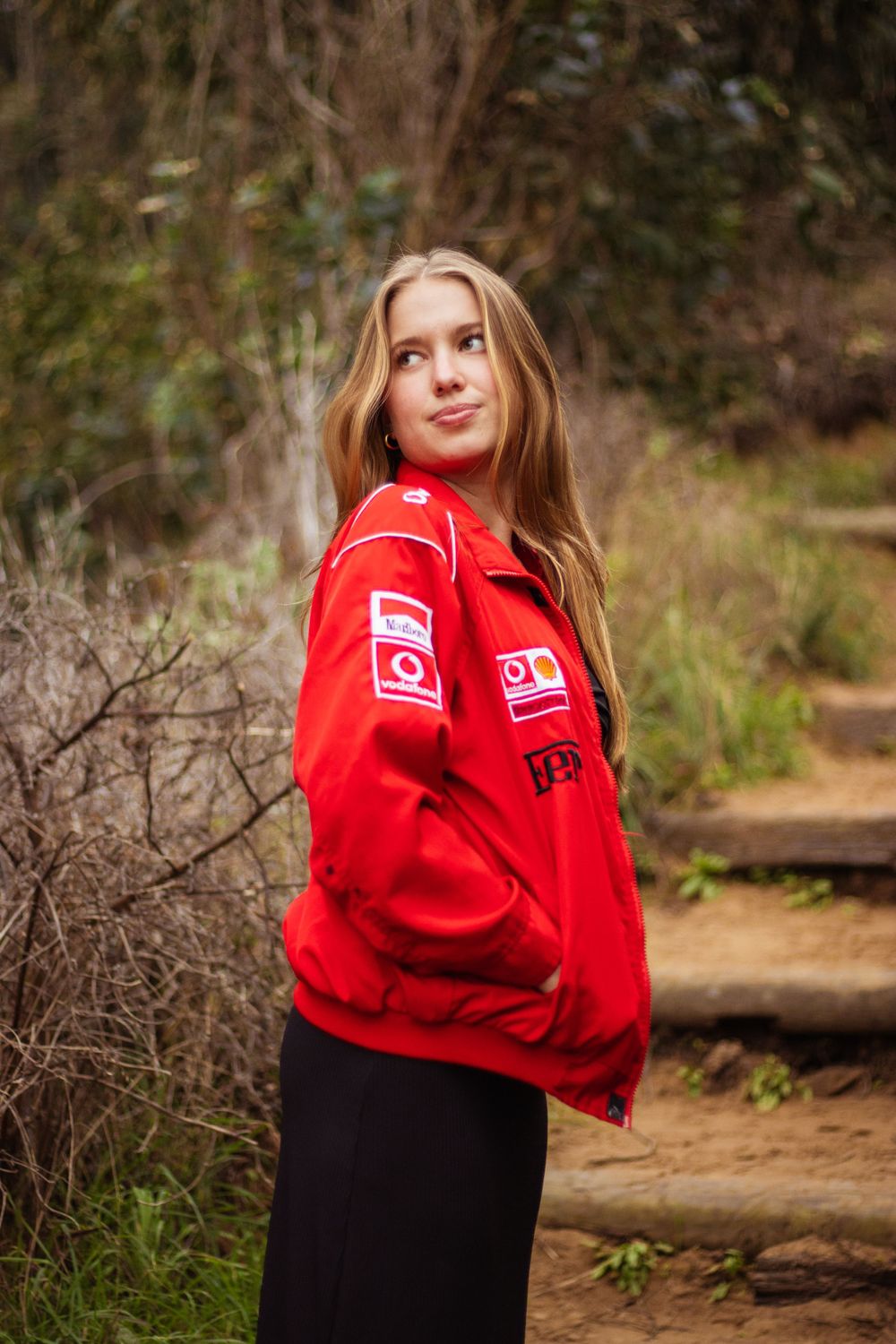 Person wearing bright red sports jacket poses on nature trail steps.
