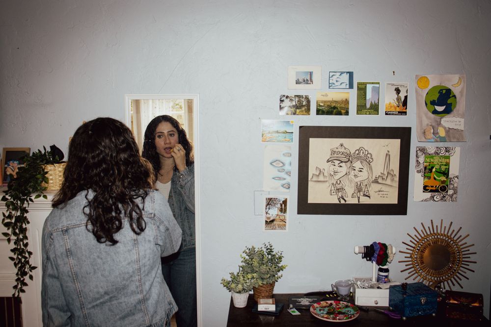 Person taking photo of themselves in mirror with indoor plants and wall art visible.