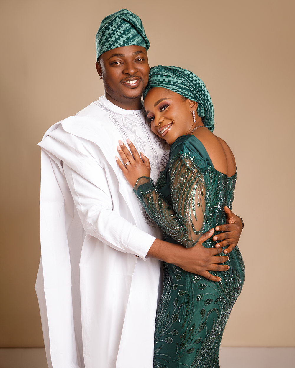 Couple in matching teal and white traditional African formal wear embrace lovingly during photo session.