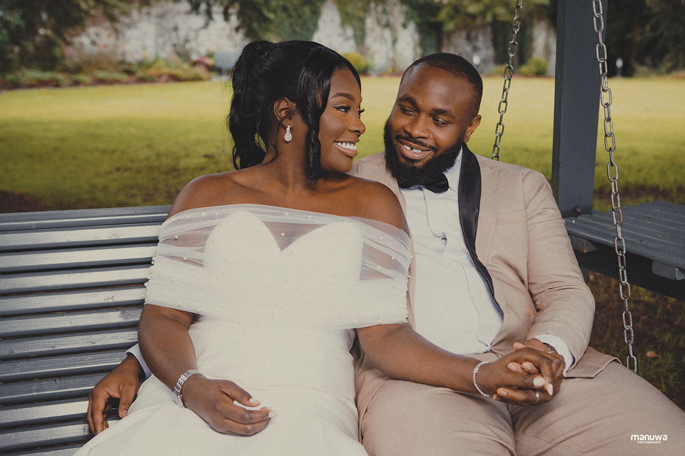 A happy couple shares a tender moment while sitting together on a garden swing.