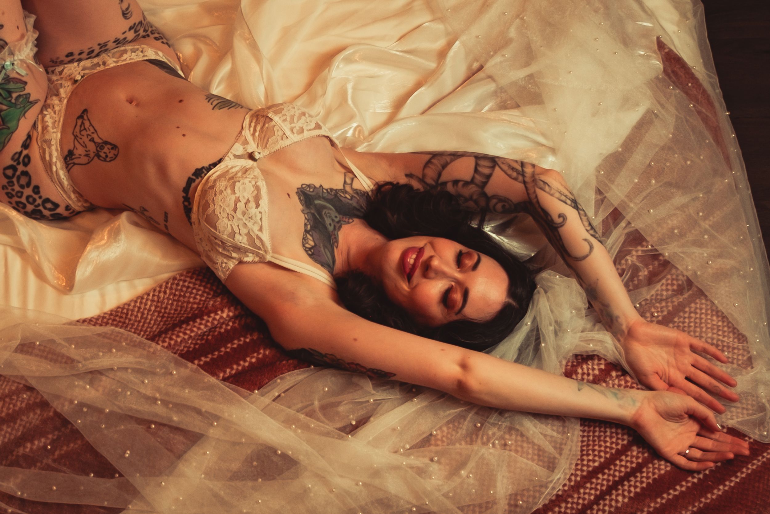 Artistic bridal boudoir photo with lace lingerie and crystals on textured fabric in warm tones.