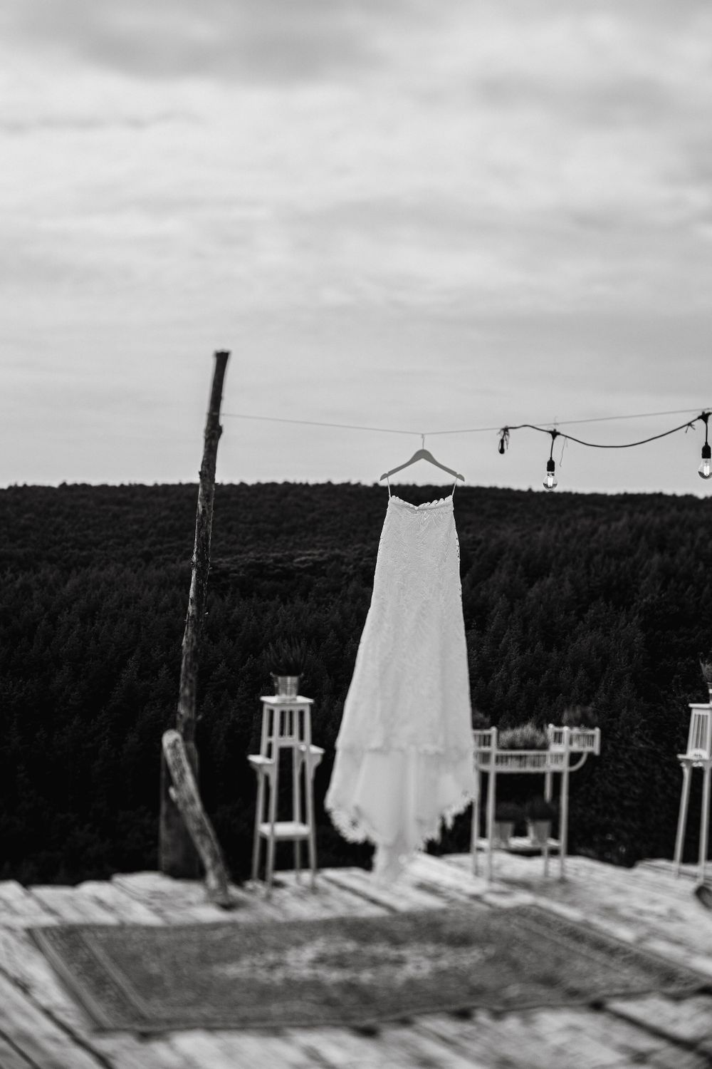 Wedding dress hanging on clothesline against forest backdrop.