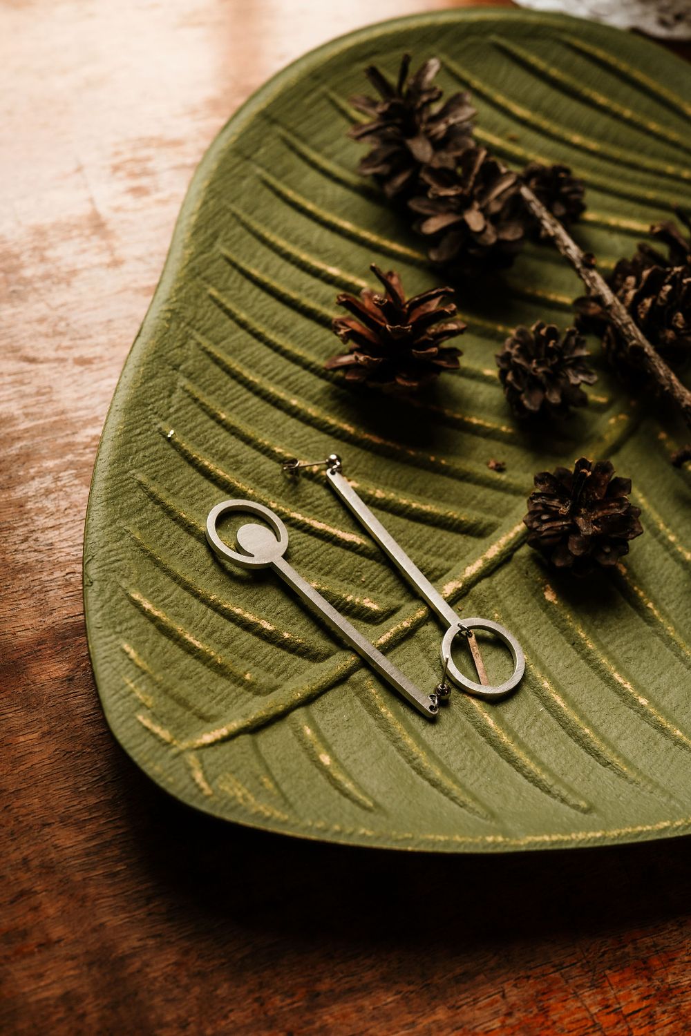 Pine cones and hair pins arranged on green leaf-shaped plate.