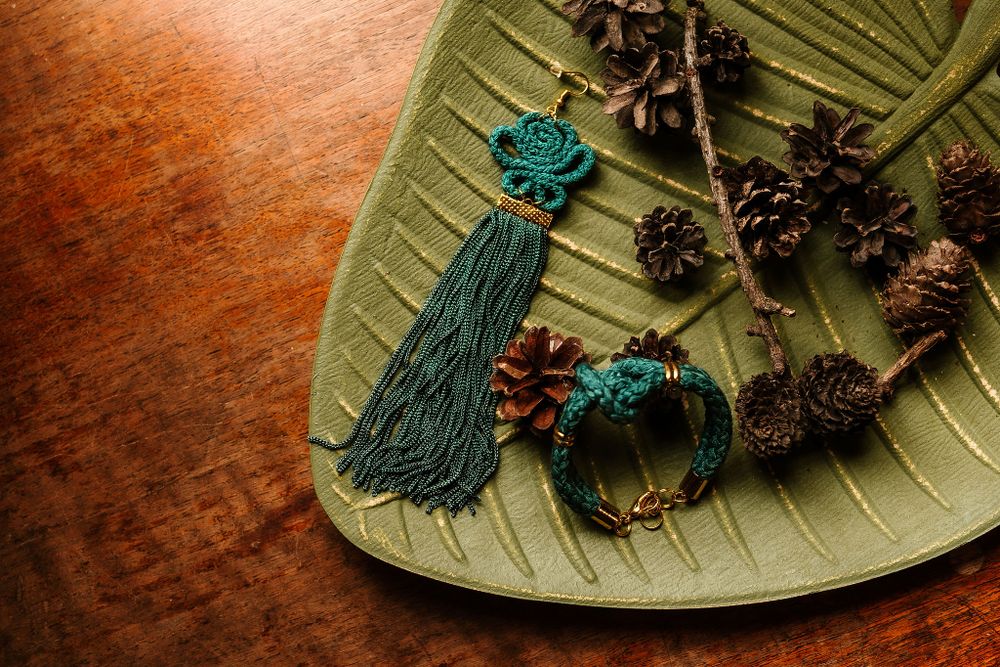 Teal tassel earrings and decorative pinecones arranged on a green leaf-shaped plate.