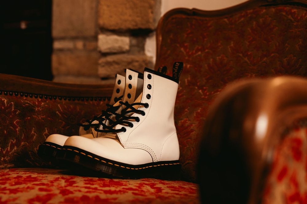 Classic white Doc Martens boot placed on a red velvet antique sofa.