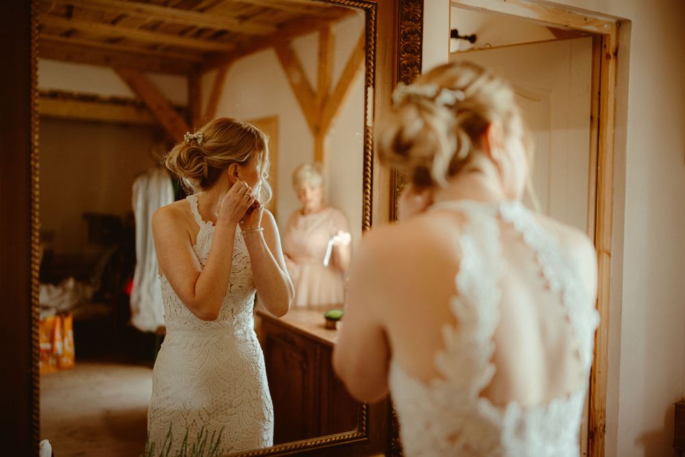 Wedding dress preparation moment captured in warm, rustic setting.