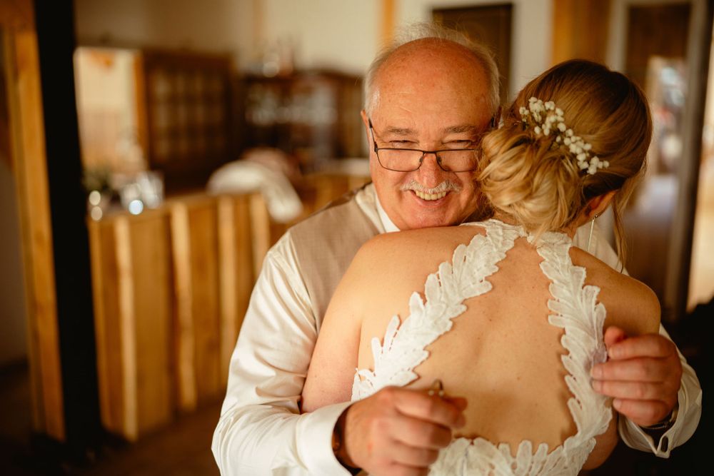 An emotional embrace during a wedding celebration in warm indoor lighting.