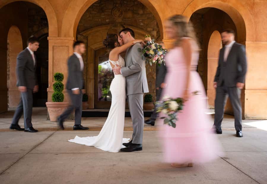 Wedding party members walk beneath arched stone columns creating artistic shadows and movement at Columbus Ohio Wedding Venue