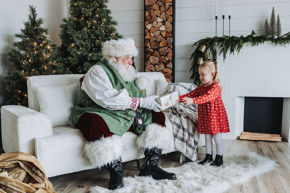 A cozy living room decorated for Christmas with a tree, firewood storage, and white modern furniture.