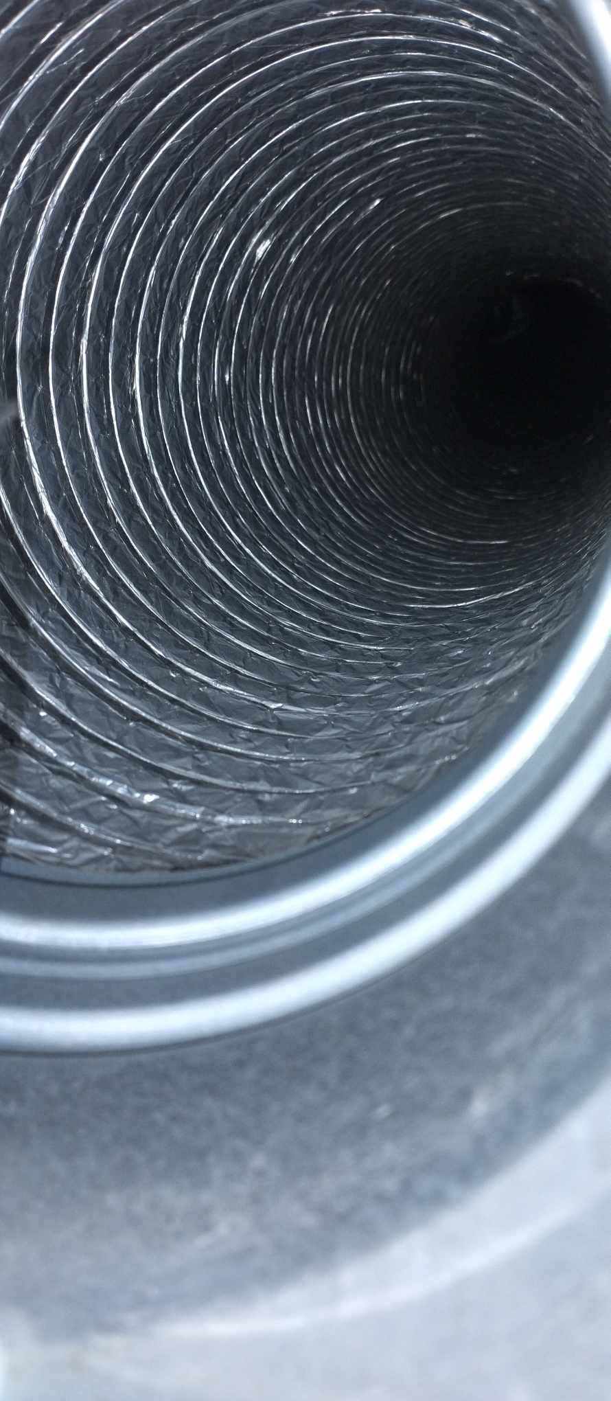 Close-up view of spiral metal ductwork interior showing ribbed surface texture.