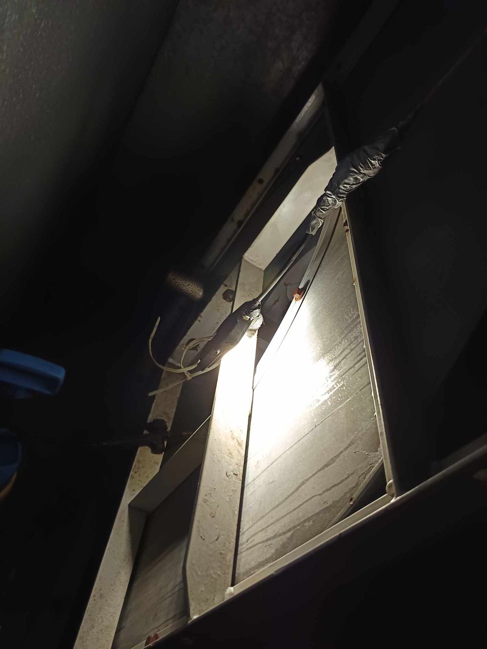 Angled metal panels or ducts illuminated against dark background in industrial setting.