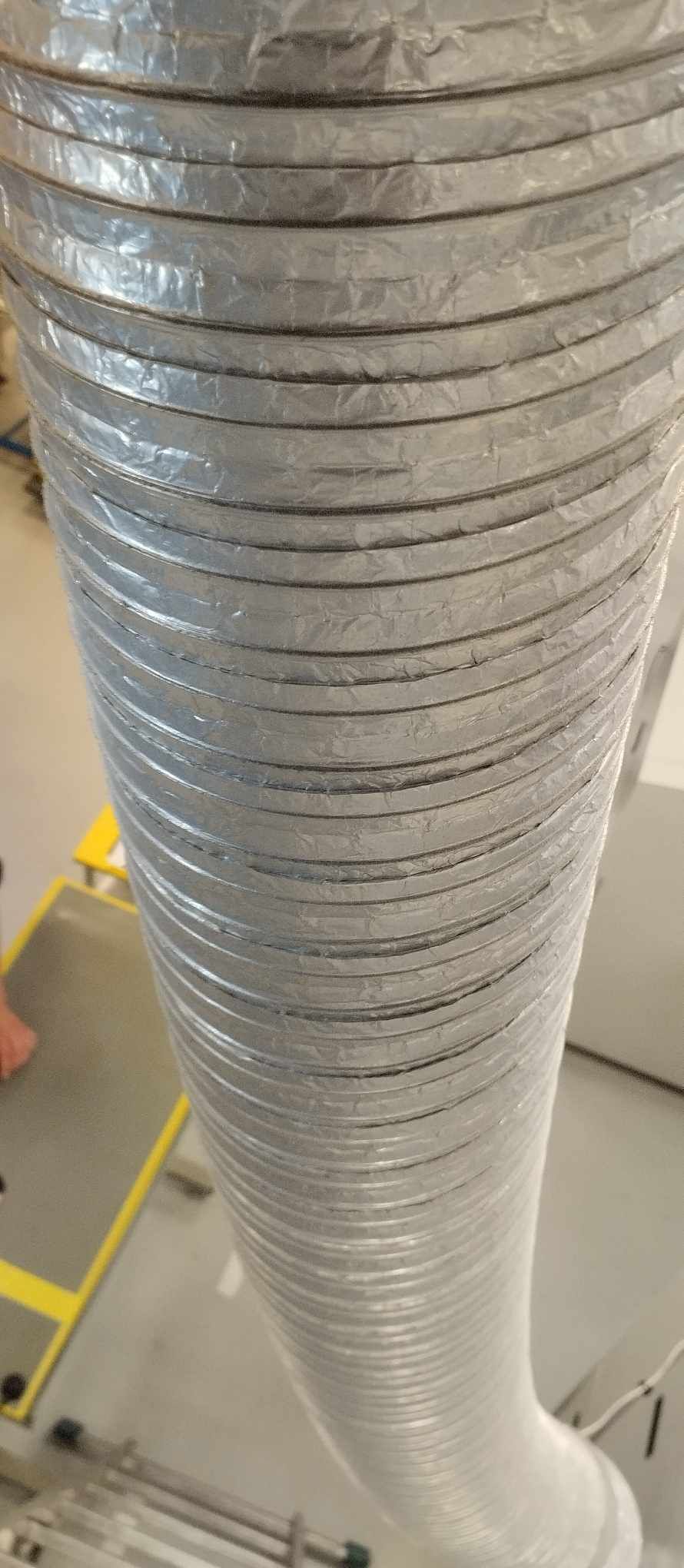 Flexible silver ventilation duct with spiral reinforcement coils visible along its length.