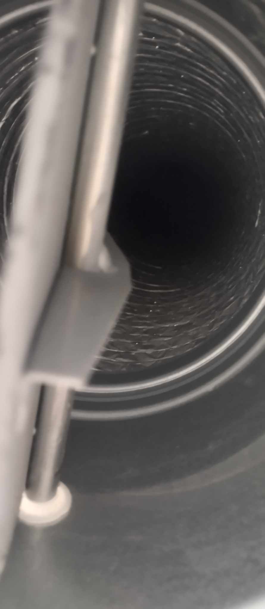 Detailed view inside metallic ventilation duct showing spiral construction pattern.