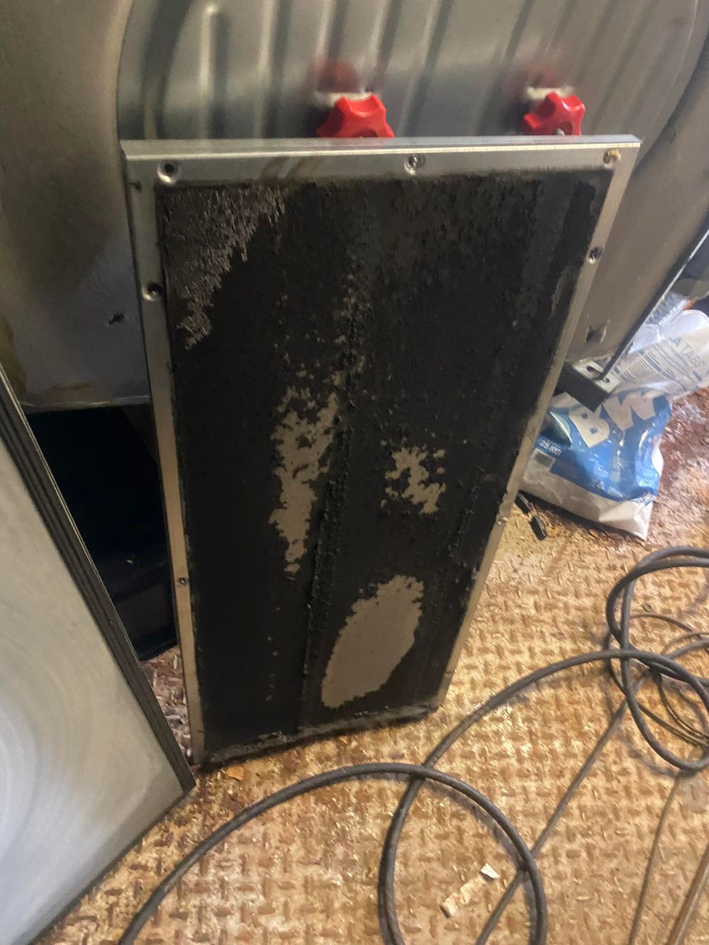 Close-up view of a damaged black electrical panel with exposed wiring and corrosion.