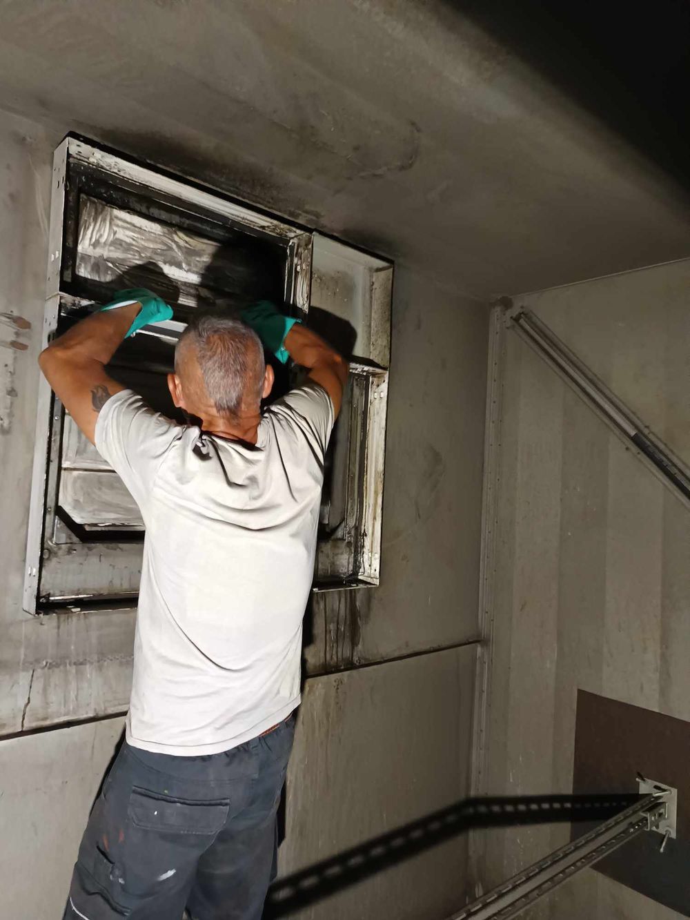 Maintenance inspection of ventilation ducts in a confined industrial space.