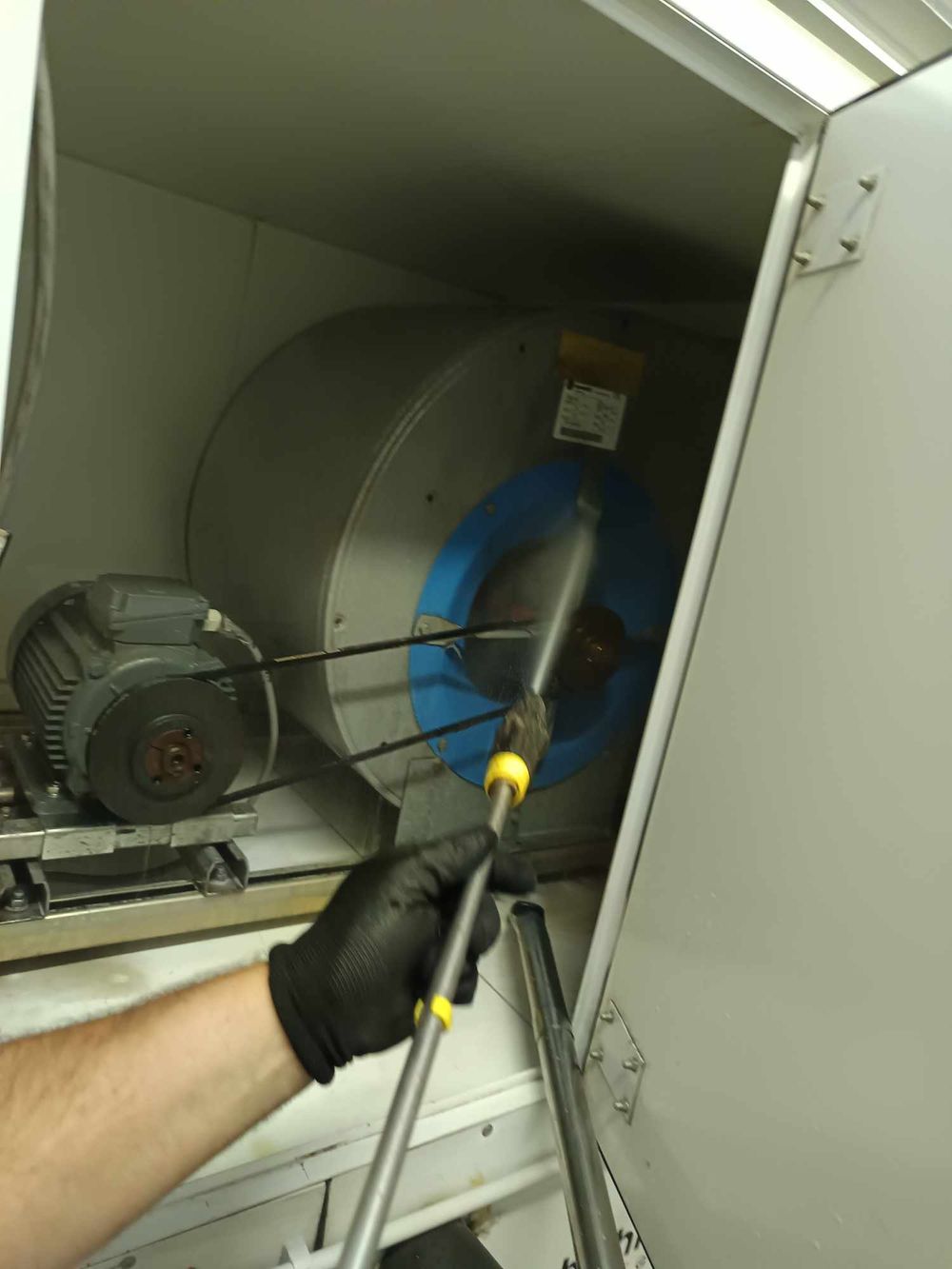Close-up of hands servicing electrical motors and equipment in an industrial cabinet.