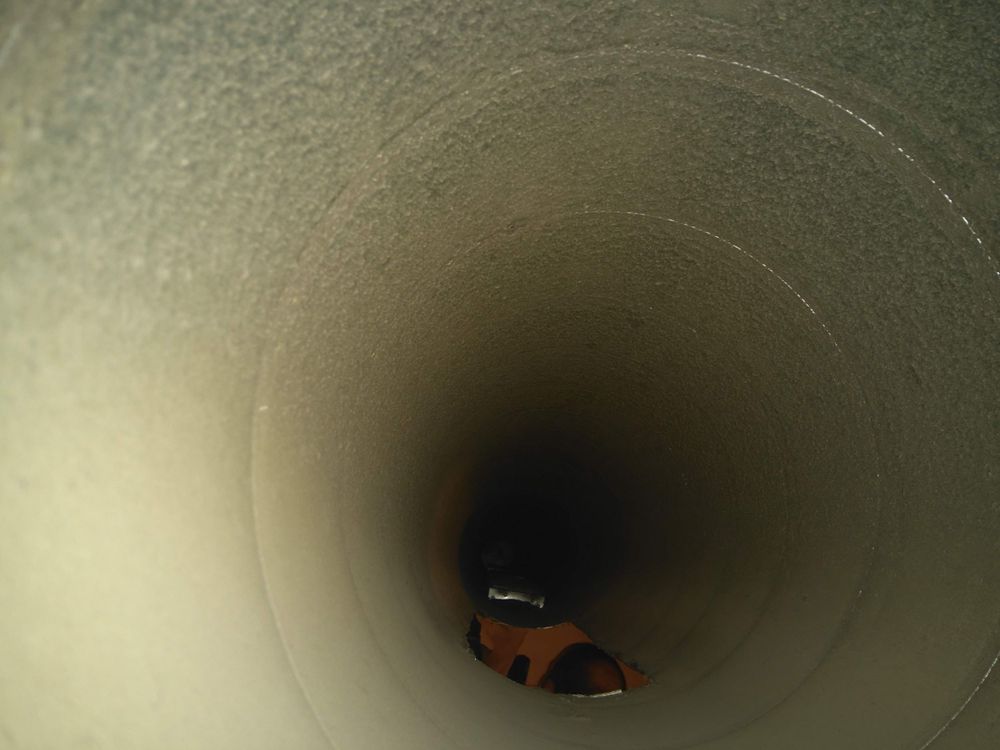 Interior view looking down a dark cylindrical duct or ventilation shaft.