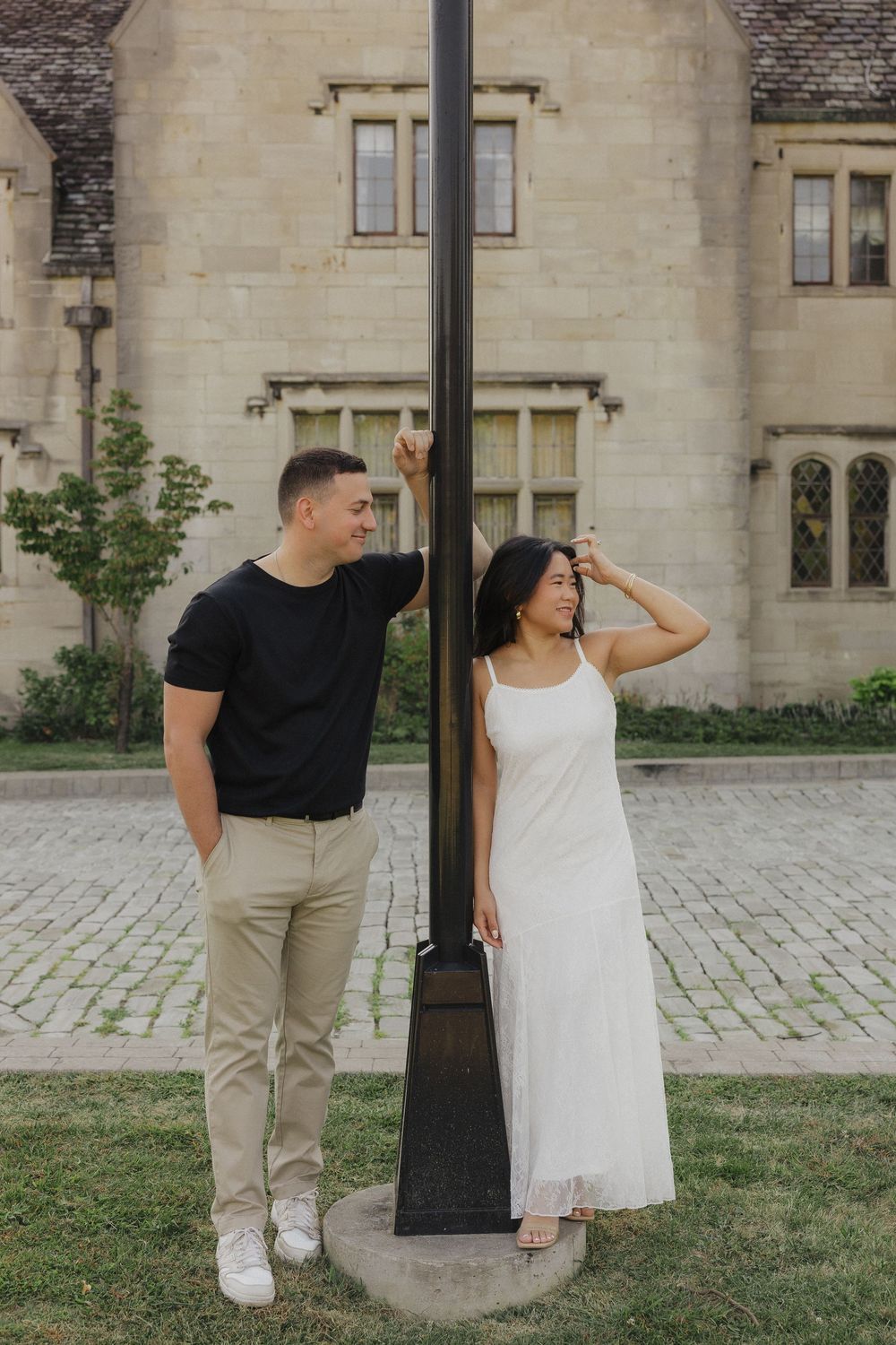 A couple poses playfully in a series of four photos against a historic stone building backdrop.