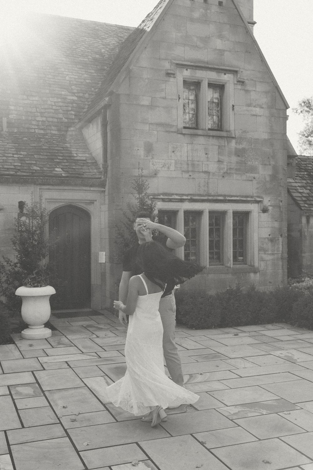 A sequence of black and white photos showing movement across a stone courtyard entrance of a historic building.