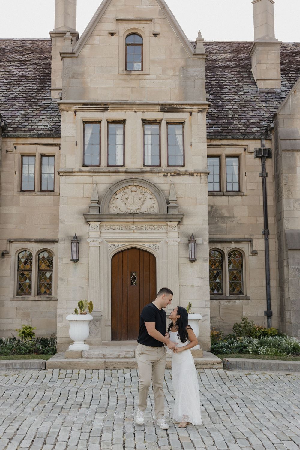 A romantic proposal scene unfolds in front of a grand stone mansion with Gothic architectural details.