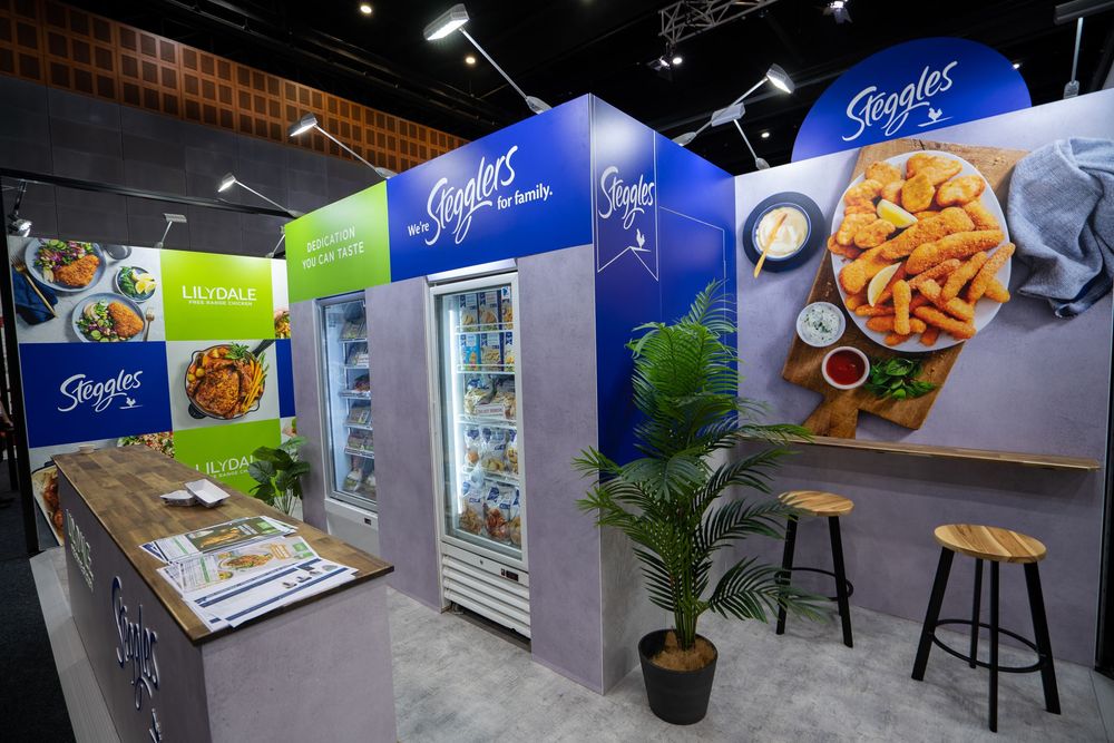 Trade show booth displays with blue walls and food product photography showcasing snacks and prepared meals.