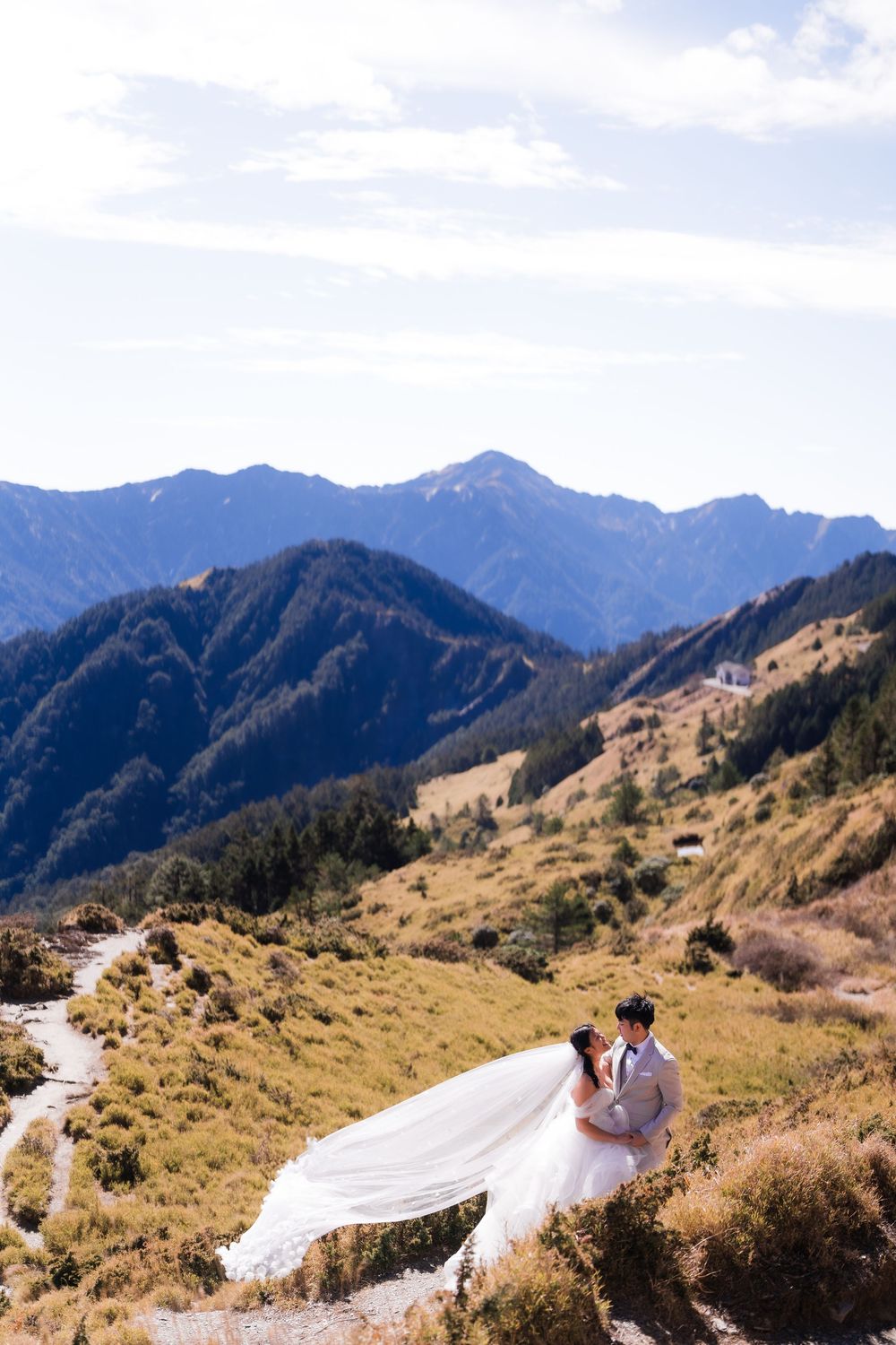 Scenic mountain landscape with winding road and couple in wedding attire against backdrop of majestic peaks at Hehuanshan, Taiwan.
