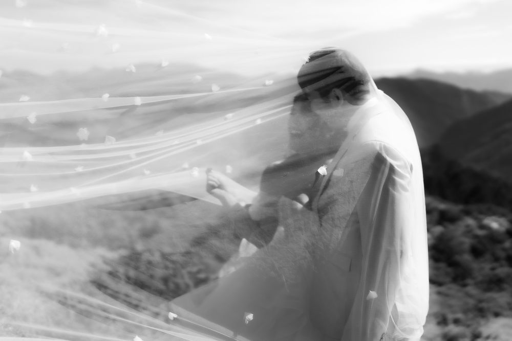 A stunning black and white photo of a bride and groom embraced under a billowing sheer veil at a mountaintop viewpoint from Hehuanshan.