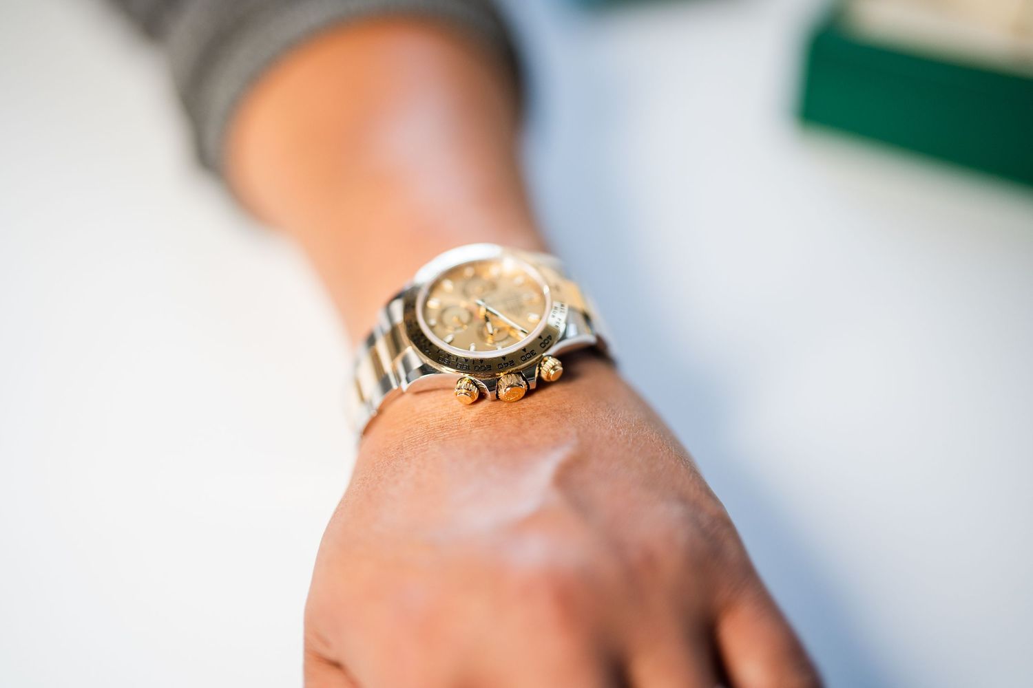 Close-up view of a gold watch with a brown leather strap displayed on a person's wrist.