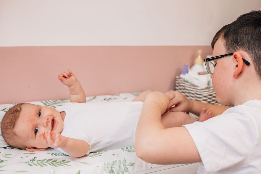 brother changing baby's nappy